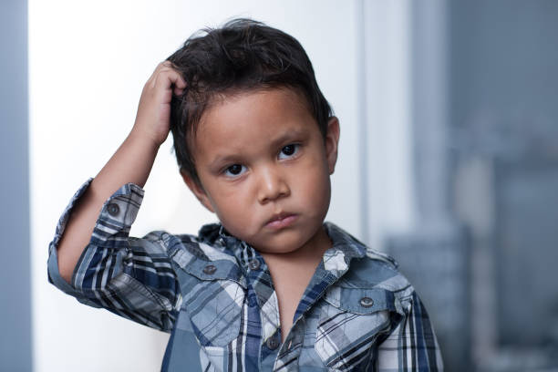 A child exibiting a mood disorder or depressed irritability, expressing sadness and pulling of his hair. stock photo