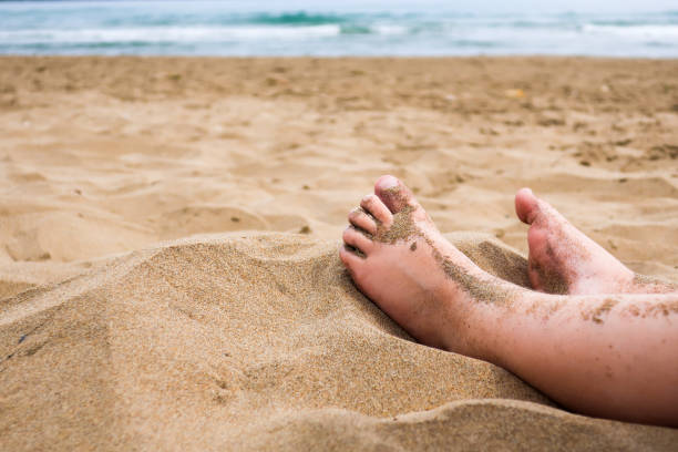 Child feet in the sand on a beach Child feet in the sand on a beach. Concept for traveling with children / family vacation and holiday. human feet buried in sand. summer beach stock pictures, royalty-free photos & images