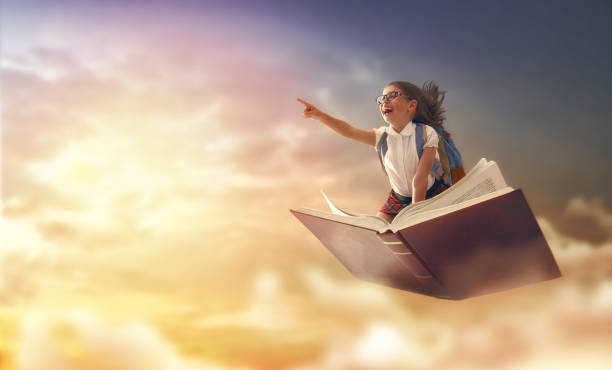 child flying on the book Back to school! Happy cute industrious child flying on the book on background of sunset sky. Concept of education and reading. The development of the imagination. imagination stock pictures, royalty-free photos & images