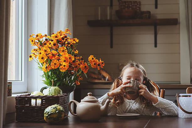 child girl having breakfast at home in autumn morning child girl having breakfast at home in autumn morning. Real life cozy modern interior in country house. Kid eating bagels and drinking tea. hot drink photos stock pictures, royalty-free photos & images
