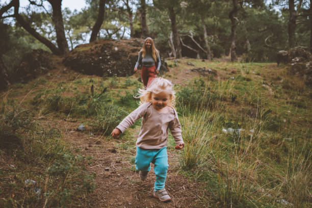 Child girl running in forest family vacations travel lifestyle 2 years old baby walking with mother outdoor happy emotions stock photo