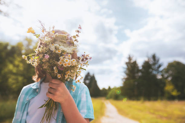 Child hidden behind a bouquet of wildflowers stock photo