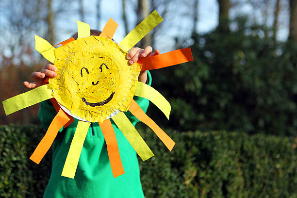 Child Holding Smiley Face Sun Outdoors stock photo