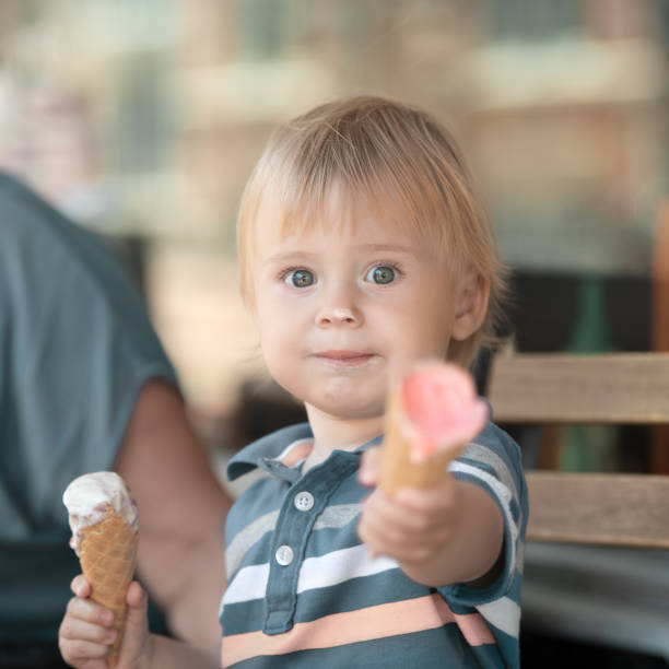 Child holds ice-cream and shares with others stock photo