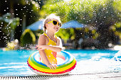 Child with goggles in swimming pool. Little girl learning to swim and dive in outdoor pool of tropical resort. Swimming with kids. Healthy sport activity for children. Sun protection. Water fun.
