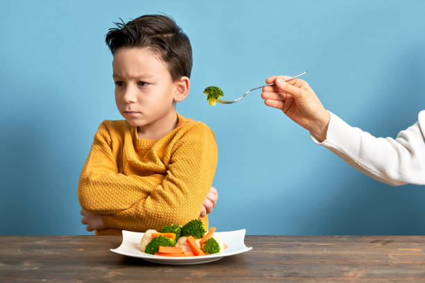 Child is very unhappy with having to eat vegetables. stock photo