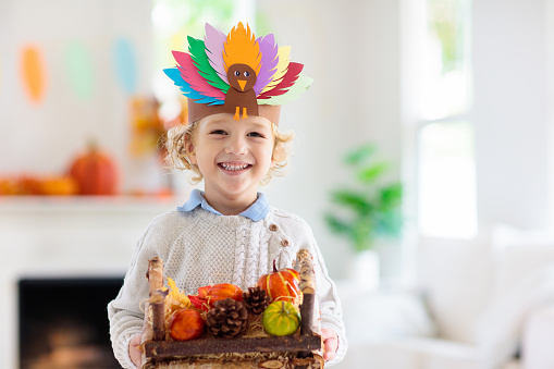 Child on Thanksgiving. Kid with autumn turkey hat.