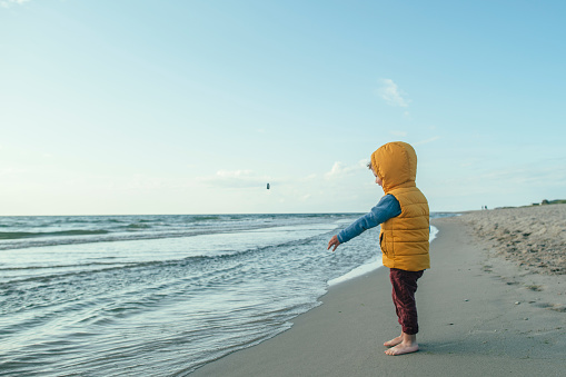 Child playing on the beach in winter or autumn