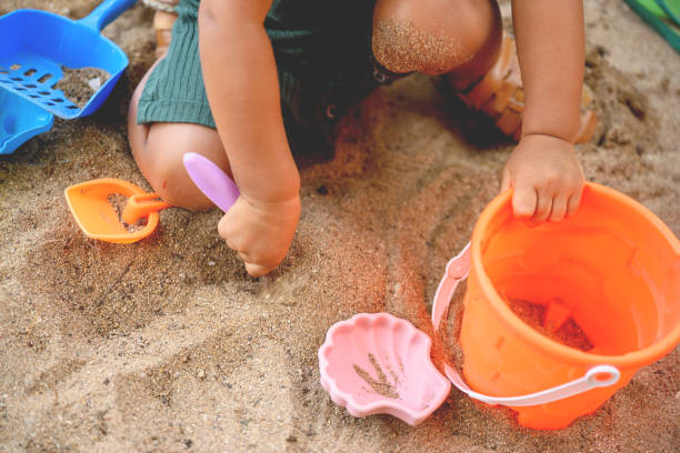child playing on the sandy beach - speelgoed stockfoto's en -beelden