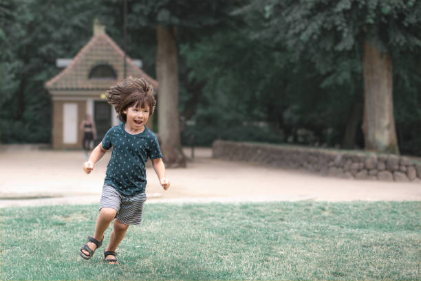 Child runs on grass in the park in the summer stock photo