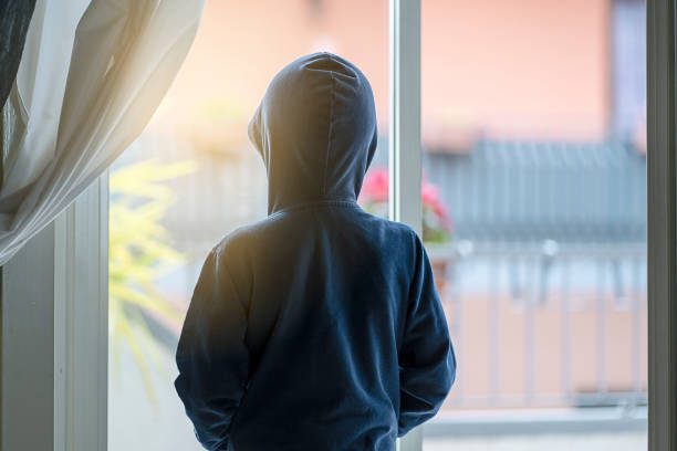 child seen from behind facing the window impossible to go out to play stock photo