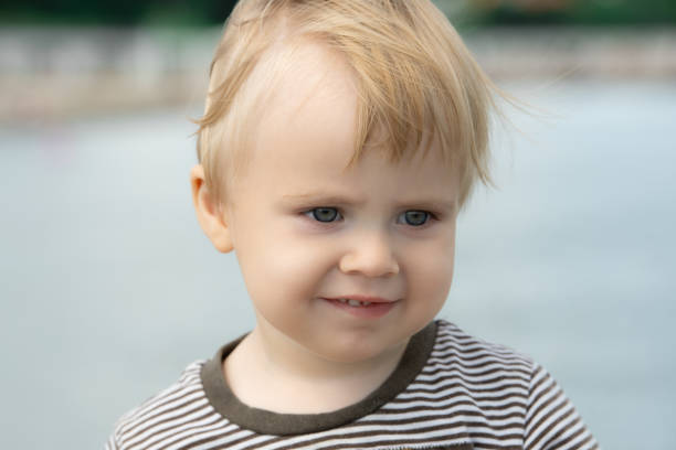 Child smiles face portrait on blue blurry sea background stock photo