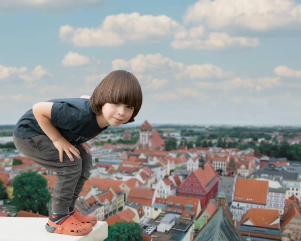 Child stays on the edge with nice city above view stock photo