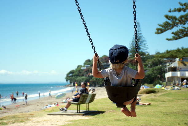 A Child swings on a Swing at a Beach Park in Summer stock photo