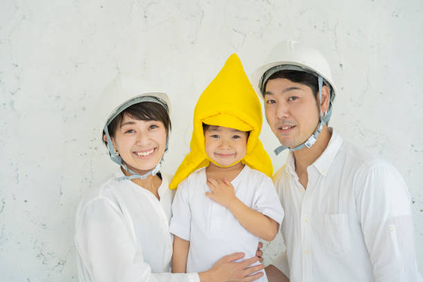 防災フードを着用した子供とヘルメットを着用した親 - 事故・災害 写真 ストックフォトと画像