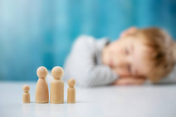 Child with wooden figures of the family on the blue background stock photo