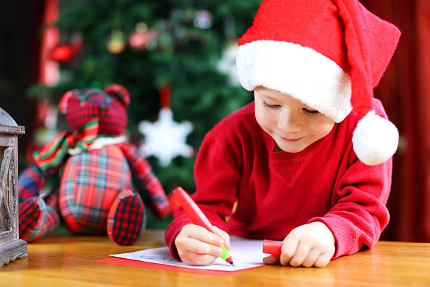 child writing a christmas letter to santa claus - a letter to santa claus, christmas gifts imagens e fotografias de stock