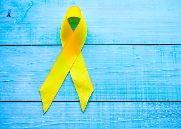 Childhood Cancer Day. Yellow Ribbon on blue background stock photo