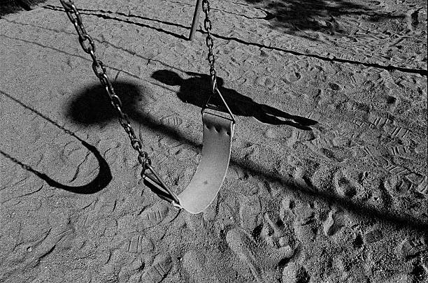 Childhood memories : empty swing with child's shadow stock photo