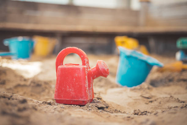 Childhood sandbox concept: Close up of plastic toy watering can Children plastic toys in the sand box. Watering can, selective focus. divorce beach stock pictures, royalty-free photos & images