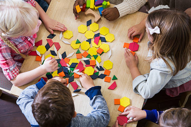 children at preschool playing with colorful shapes - blok vorm stockfoto's en -beelden