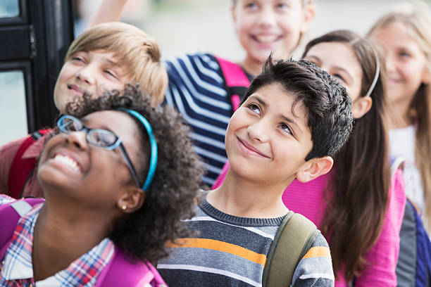 Children getting on school bus Group of multi-ethnic elementary school children getting on school bus.  Focus on boy in middle (10 years, mixed race Hispanic, Middle Eastern ethnicity). boarding schools stock pictures, royalty-free photos & images