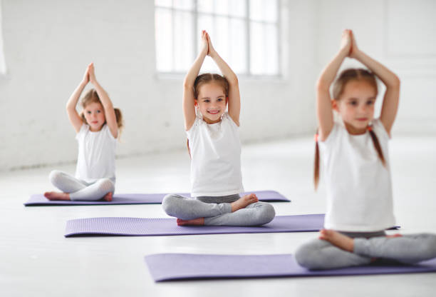children girls doing yoga and gymnastics in gym - yoga crianças imagens e fotografias de stock