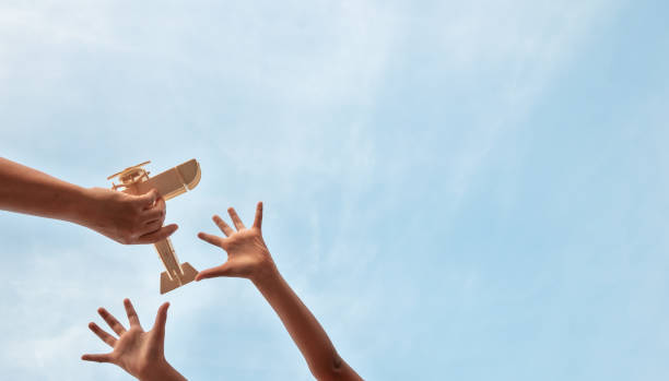 Children hands and father hands playing wooden plane toy on a beautiful sky background, Low angle view. Children hands and father hands playing wooden plane toy on a beautiful sky background, Low angle view. asian ambition stock pictures, royalty-free photos & images