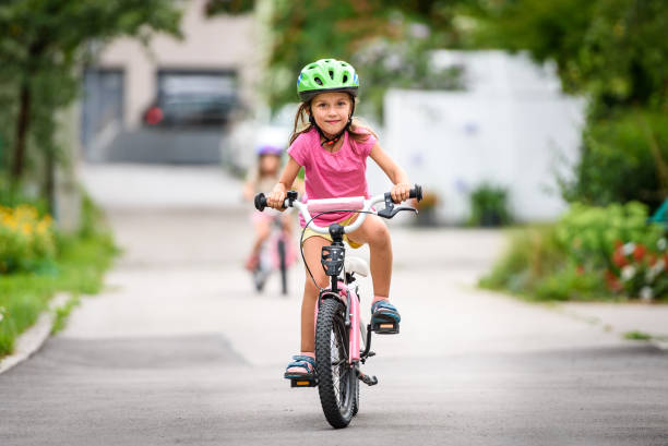 Children learning to drive a bicycle on a driveway outside. stock photo