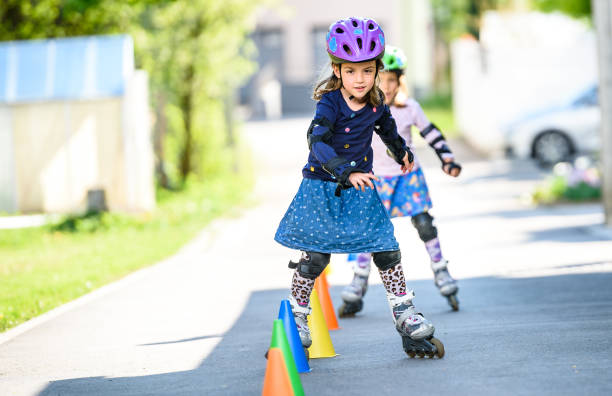 Children learning to roller skate on the road with cones. stock photo
