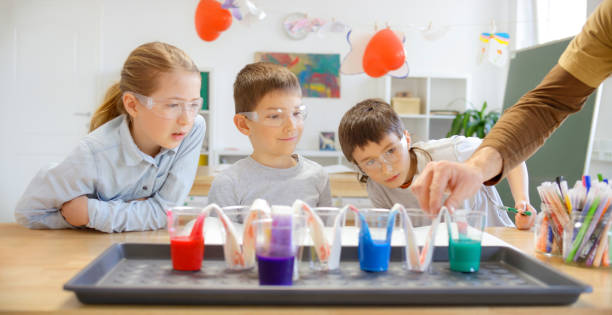 Children observing the traveling water experiment in laboratory stock photo