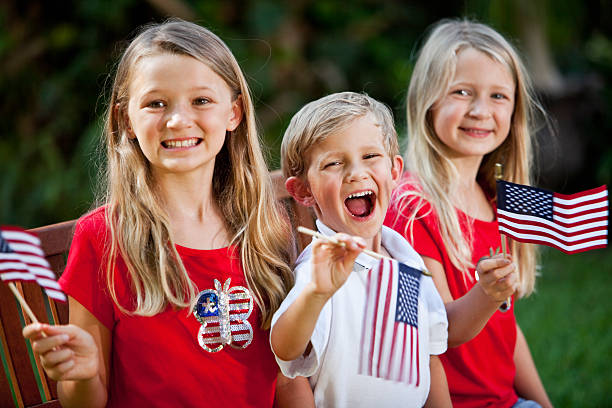 Children on Fourth of July or Memorial Day Siblings holding American Flags.  Focus on boy, 4 years. memorial day stock pictures, royalty-free photos & images
