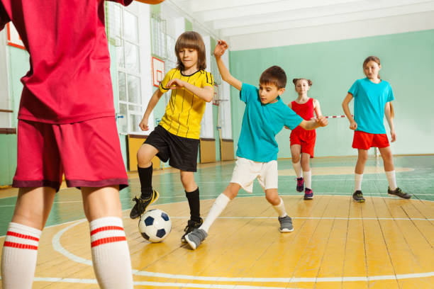 children playing football in school gymnasium - futsal imagens e fotografias de stock