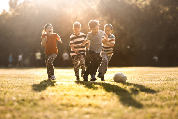 Children playing soccer on the meadow stock photo