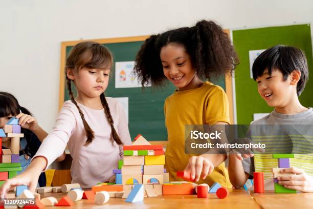 Children playing with wooden blocks in classroom