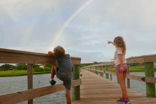 Children pointing at a double rainbow stock photo