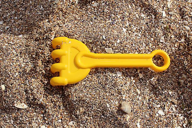 Children rake to play in the sand stock photo