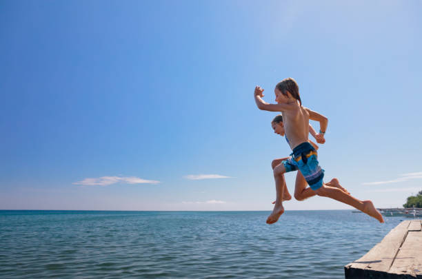 Children run, jump high into water stock photo