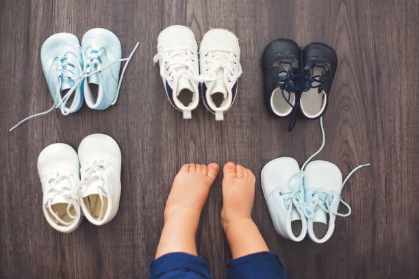 Children shoes and baby feet on a wood background stock photo