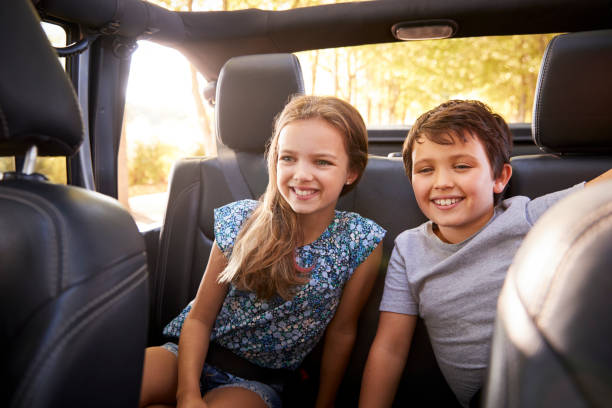 Children Sitting In Back Seat Of Open Top Car On Road Trip Children Sitting In Back Seat Of Open Top Car On Road Trip back seat stock pictures, royalty-free photos & images