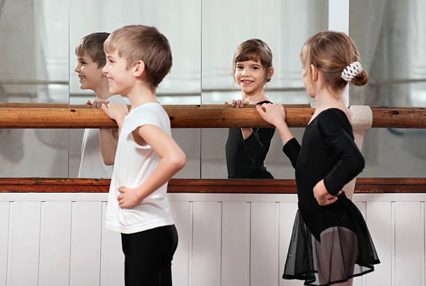 children standing at ballet barre stock photo