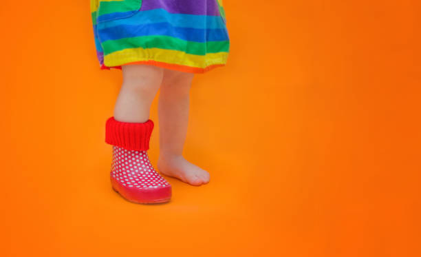 children's foot in one rubber boot. one leg is bare - barefoot. baby lost her boot. the concept of spring, summertime, colorfulness and the first steps of a toddler. - lost first imagens e fotografias de stock