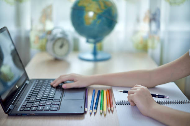 children's hand types on the keyboard during homework stock photo