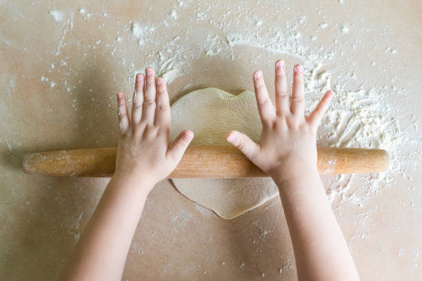 Children's hands rolled dough Top view shoot of children's hands rolled dough with a rolling pin on the table cooking class stock pictures, royalty-free photos & images
