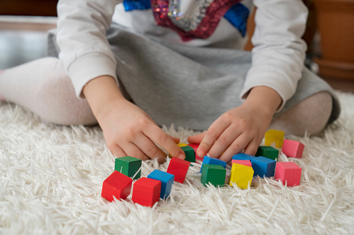 child's hand playing with colorful wooden blocks