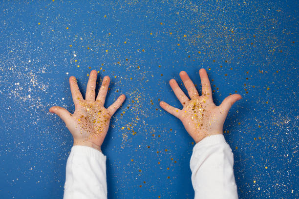 Child's hands holding golden stars on sparkling blue background. stock photo