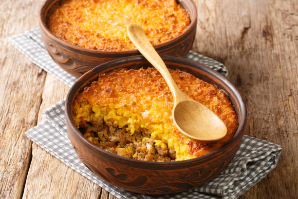 Chilean shepherd's pie, pastel de choclo tops spiced ground beef with a puréed corn crust closeup in the pots. Horizontal stock photo