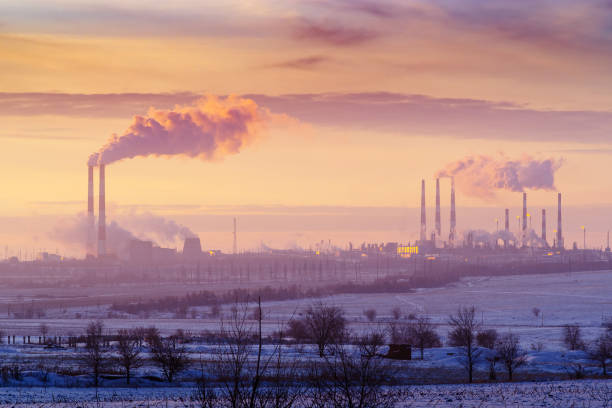 Chimneys and cooling towers at sunset. A combined heat and power plant and gas processing plant on the horizon stock photo