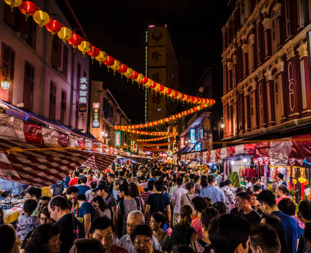 シンガポールの旧正月のお祝いの間にチャイナタウンの通りを歩く群衆。多くの人々は、この人気のお祝いの間に夜遅くまで開く多くの市場の屋台で祝い、食べて、購入します。
