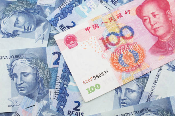 A Chinese one hundred yuan note on a background of Brazilian real notes stock photo